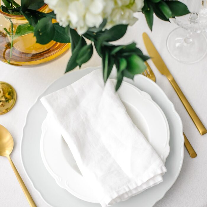 Elegance classic table setting with white dishes, gold cutlery and hydrangea flower