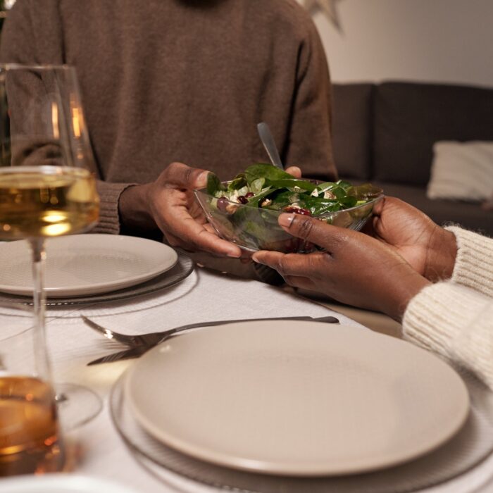 Hands of young African couple holding bowl with salad